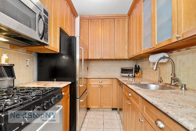 kitchen featuring sink, appliances with stainless steel finishes, tasteful backsplash, light stone countertops, and light tile patterned flooring