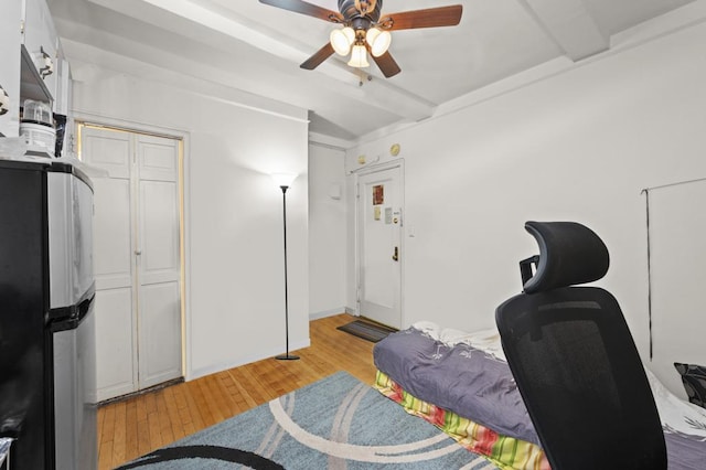 interior space featuring beamed ceiling, light wood-style floors, freestanding refrigerator, and ceiling fan