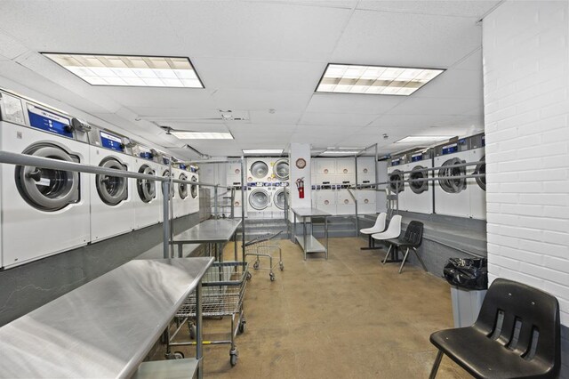 workout area featuring stacked washer / drying machine, a drop ceiling, and independent washer and dryer