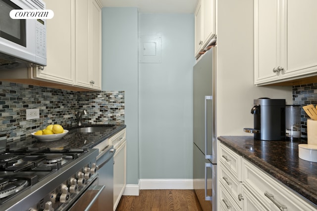 kitchen featuring white cabinetry, appliances with stainless steel finishes, and dark stone counters