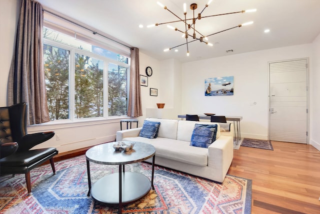 living room featuring an inviting chandelier, light hardwood / wood-style flooring, and plenty of natural light