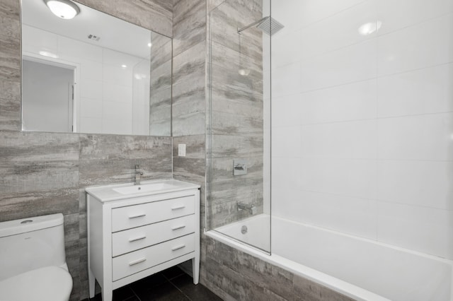 full bathroom with toilet, tiled shower / bath, tile walls, vanity, and tile patterned floors