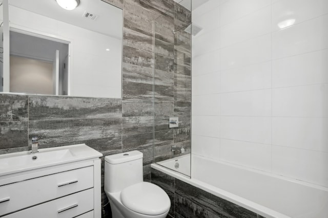 full bathroom featuring tile walls, toilet, vanity, and tiled shower / bath