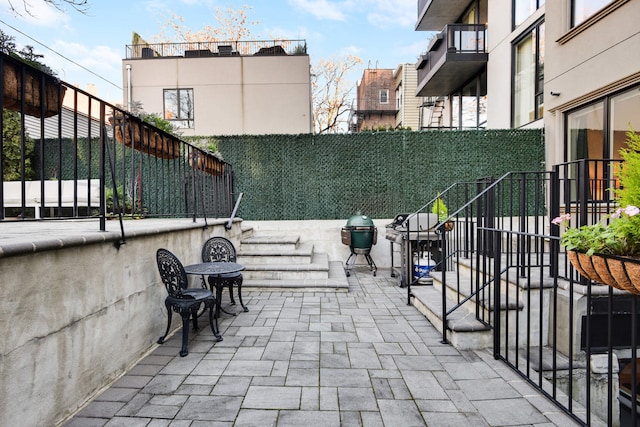 view of patio with a grill, stairs, and fence