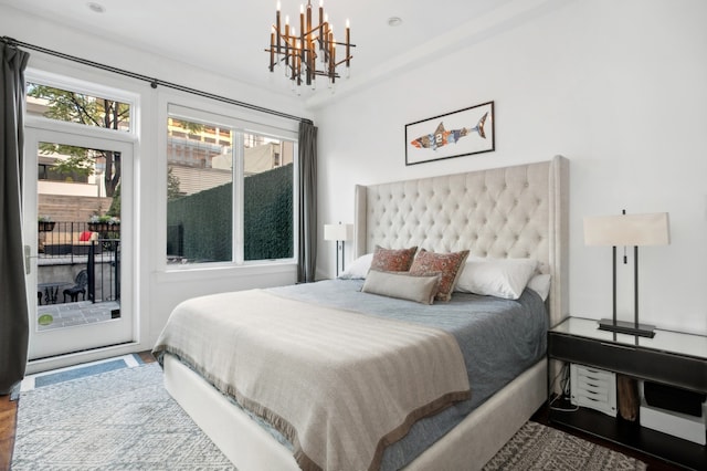 bedroom with a chandelier, access to outside, and wood finished floors