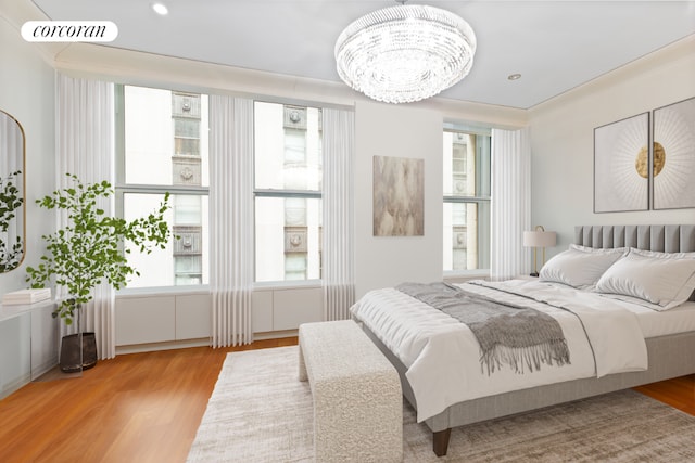 bedroom with light wood-type flooring, a notable chandelier, and multiple windows