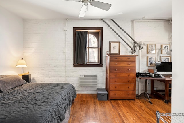 210 Spring St Unit 5Fl, New York City, NY 10013 - bedroom with brick wall, an AC wall unit, hardwood / wood-style floors, and a ceiling fan