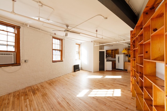 210 Spring St Unit 5Fl, New York City, NY 10013 - unfurnished living room featuring wood-type flooring, brick wall, separate washer and dryer, cooling unit, and a ceiling fan