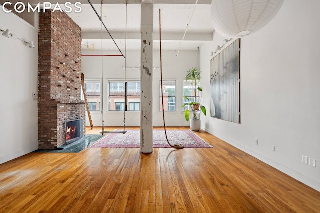 unfurnished living room featuring a brick fireplace, a wealth of natural light, and hardwood / wood-style flooring