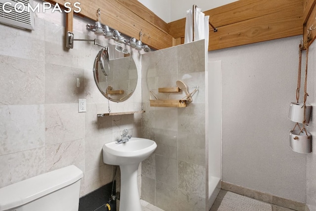 bathroom with toilet, tile walls, and tile patterned flooring