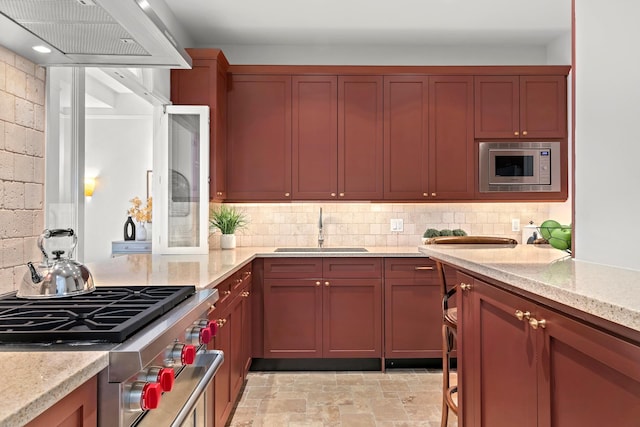 kitchen featuring stainless steel appliances, decorative backsplash, a sink, custom range hood, and stone finish flooring