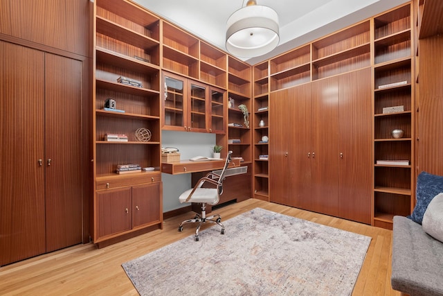 home office featuring light wood finished floors and built in study area