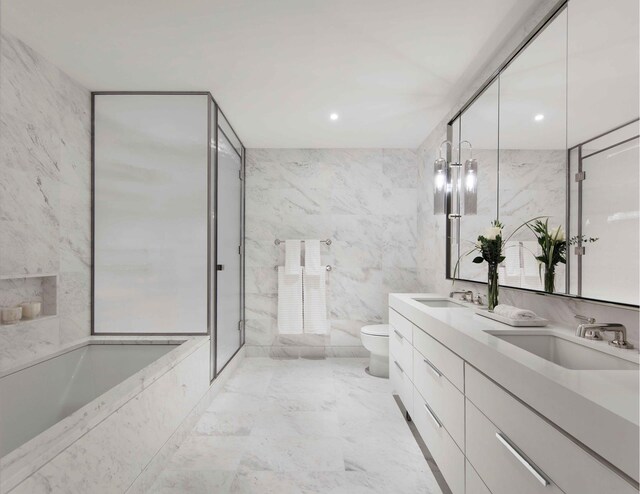 full bathroom featuring toilet, a sink, a garden tub, marble finish floor, and tile walls