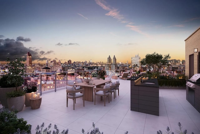 patio terrace at dusk with a skyline view, a sink, and outdoor dining area