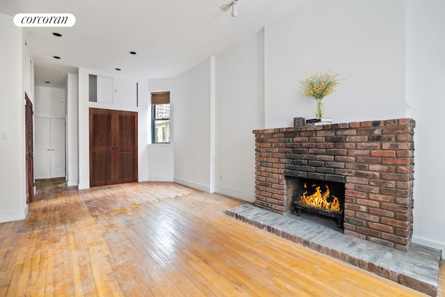 unfurnished living room featuring hardwood / wood-style floors, a fireplace, visible vents, and baseboards