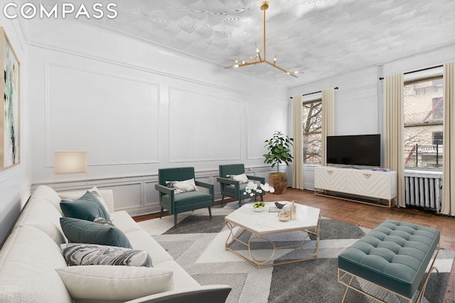 living room with parquet flooring, a textured ceiling, radiator, and an inviting chandelier