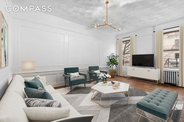 living area featuring radiator, a notable chandelier, and a decorative wall