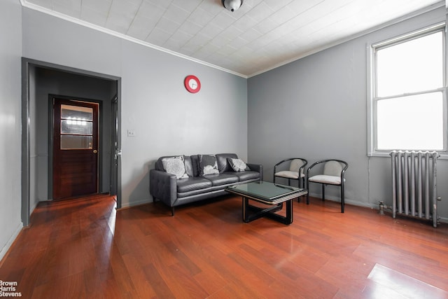 living area featuring crown molding, baseboards, radiator heating unit, and wood finished floors