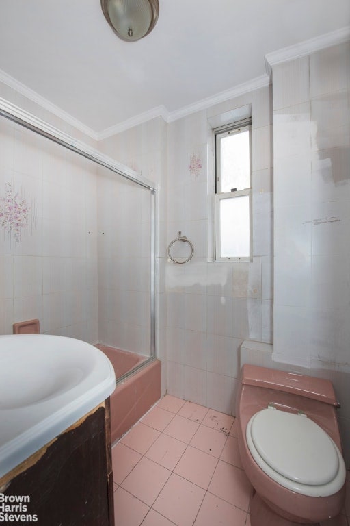 full bath featuring combined bath / shower with glass door, vanity, tile walls, and crown molding