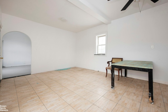 tiled empty room featuring arched walkways and a ceiling fan