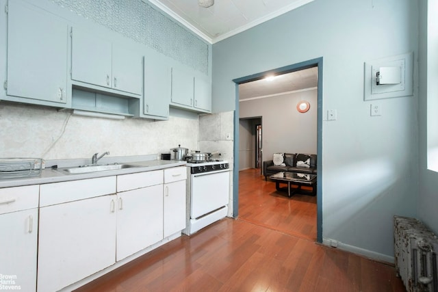 kitchen with a sink, white range with gas cooktop, light countertops, radiator, and crown molding