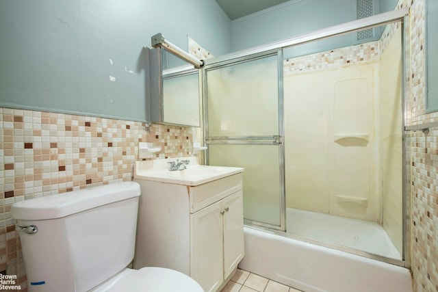 bathroom with toilet, enclosed tub / shower combo, tile patterned floors, vanity, and tile walls