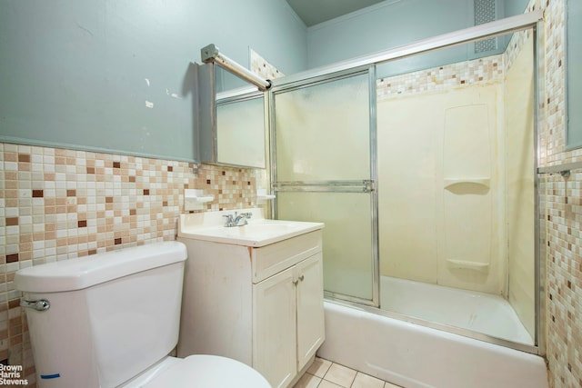 full bath with vanity, tile patterned flooring, toilet, tile walls, and combined bath / shower with glass door