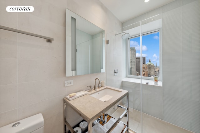 bathroom with a city view, tile walls, toilet, a stall shower, and a sink