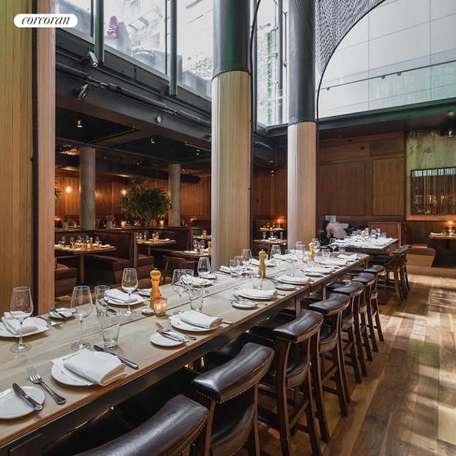 dining area with a towering ceiling, wood walls, and wood finished floors