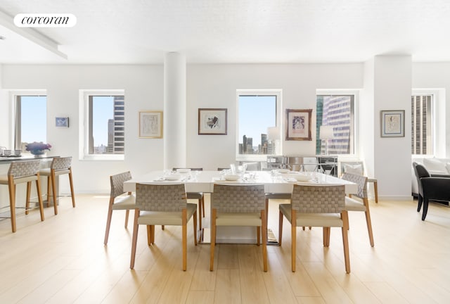 dining area with light wood-type flooring, visible vents, and baseboards