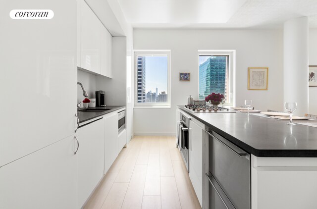 kitchen with white cabinets, dark countertops, modern cabinets, stainless steel appliances, and a sink