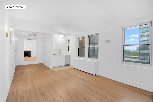 unfurnished room featuring radiator heating unit and light wood-type flooring