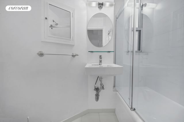 bathroom with shower / bath combination with glass door, tile patterned flooring, and baseboards