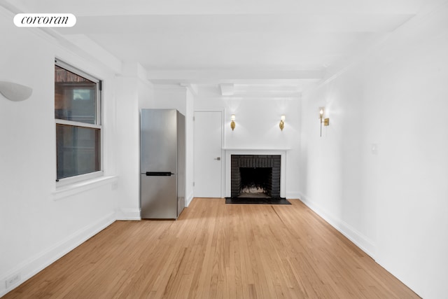 unfurnished living room featuring a brick fireplace and light hardwood / wood-style flooring