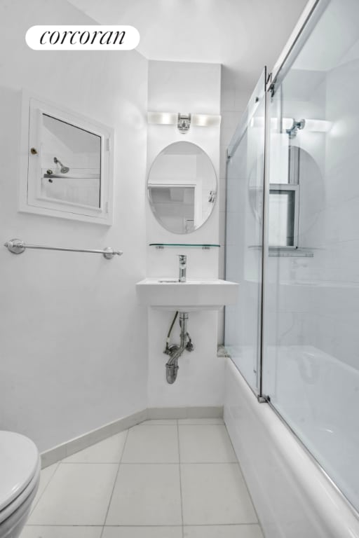 bathroom with bath / shower combo with glass door, tile patterned floors, and toilet