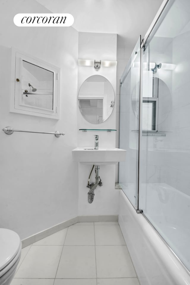 full bath featuring bath / shower combo with glass door, tile patterned flooring, toilet, and baseboards