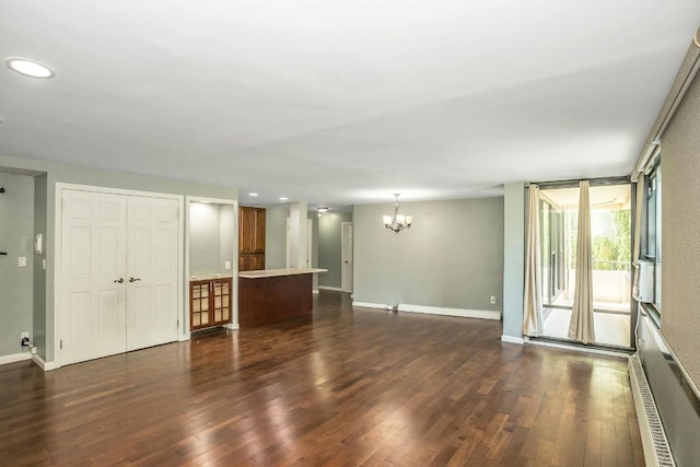 empty room featuring a baseboard heating unit, dark hardwood / wood-style flooring, and a chandelier