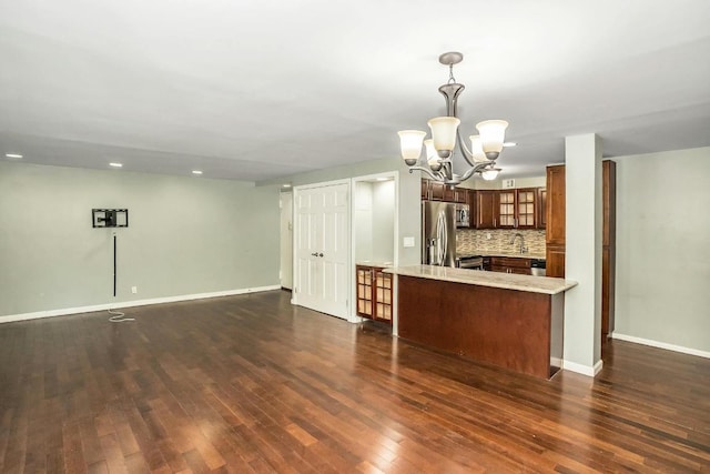 kitchen with decorative light fixtures, decorative backsplash, stainless steel fridge, dark hardwood / wood-style floors, and kitchen peninsula