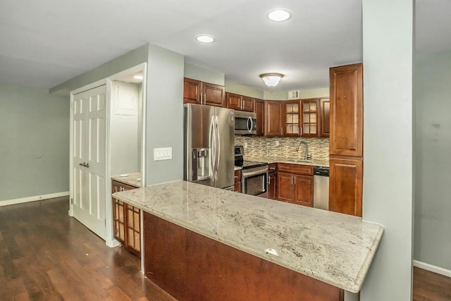 kitchen with light stone countertops, kitchen peninsula, stainless steel appliances, and tasteful backsplash