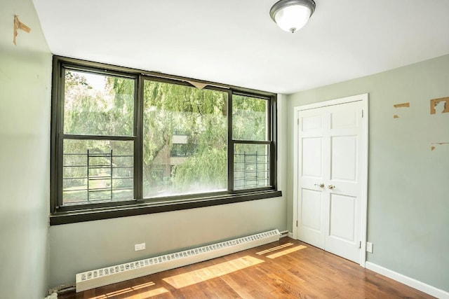 empty room with hardwood / wood-style floors and a baseboard radiator