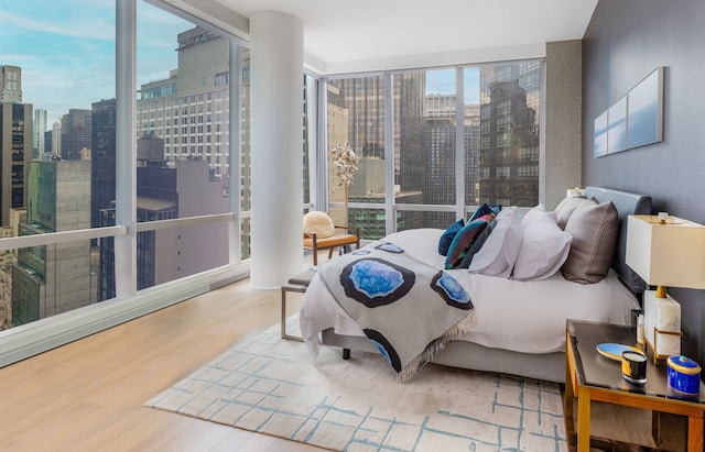 bedroom with a view of city and wood finished floors