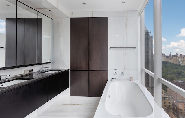 full bathroom featuring double vanity, a city view, a sink, and a bath