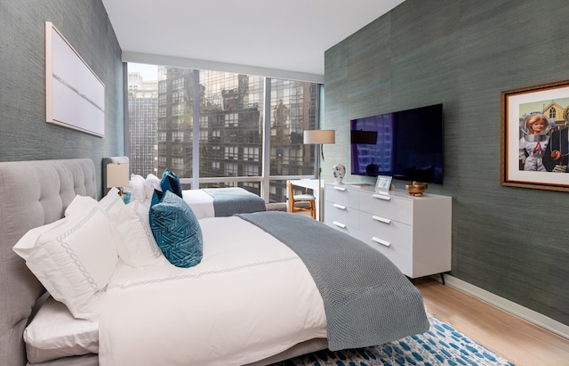 bedroom with wallpapered walls, baseboards, and wood finished floors