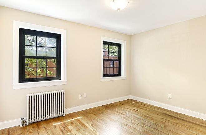 empty room with hardwood / wood-style flooring, plenty of natural light, and radiator