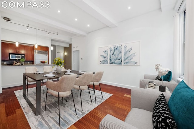 dining room with beamed ceiling, rail lighting, and dark hardwood / wood-style floors