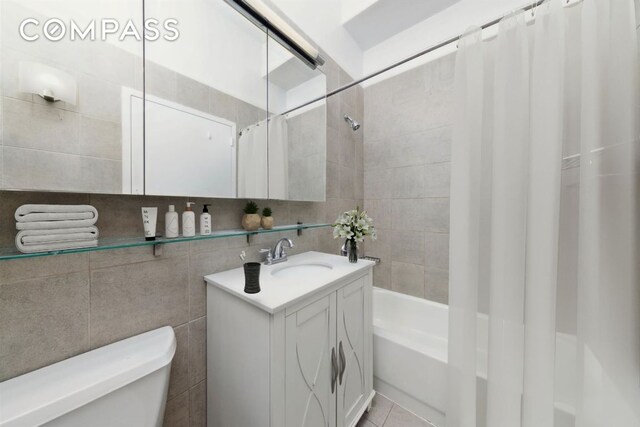 full bathroom with shower / bathtub combination with curtain, tile patterned floors, toilet, tile walls, and vanity