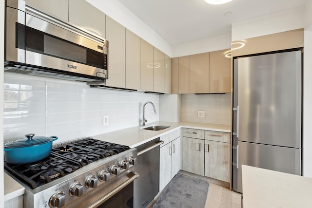 kitchen with stainless steel appliances, backsplash, a sink, and light countertops