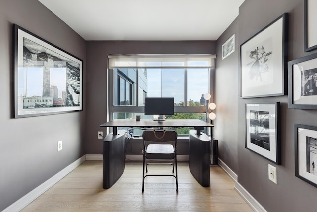 office space featuring light wood-style flooring, visible vents, and baseboards