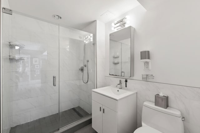 full bathroom with a stall shower, tile walls, toilet, and vanity