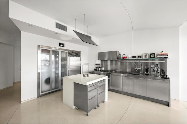 kitchen with sink, backsplash, stainless steel built in fridge, and an island with sink